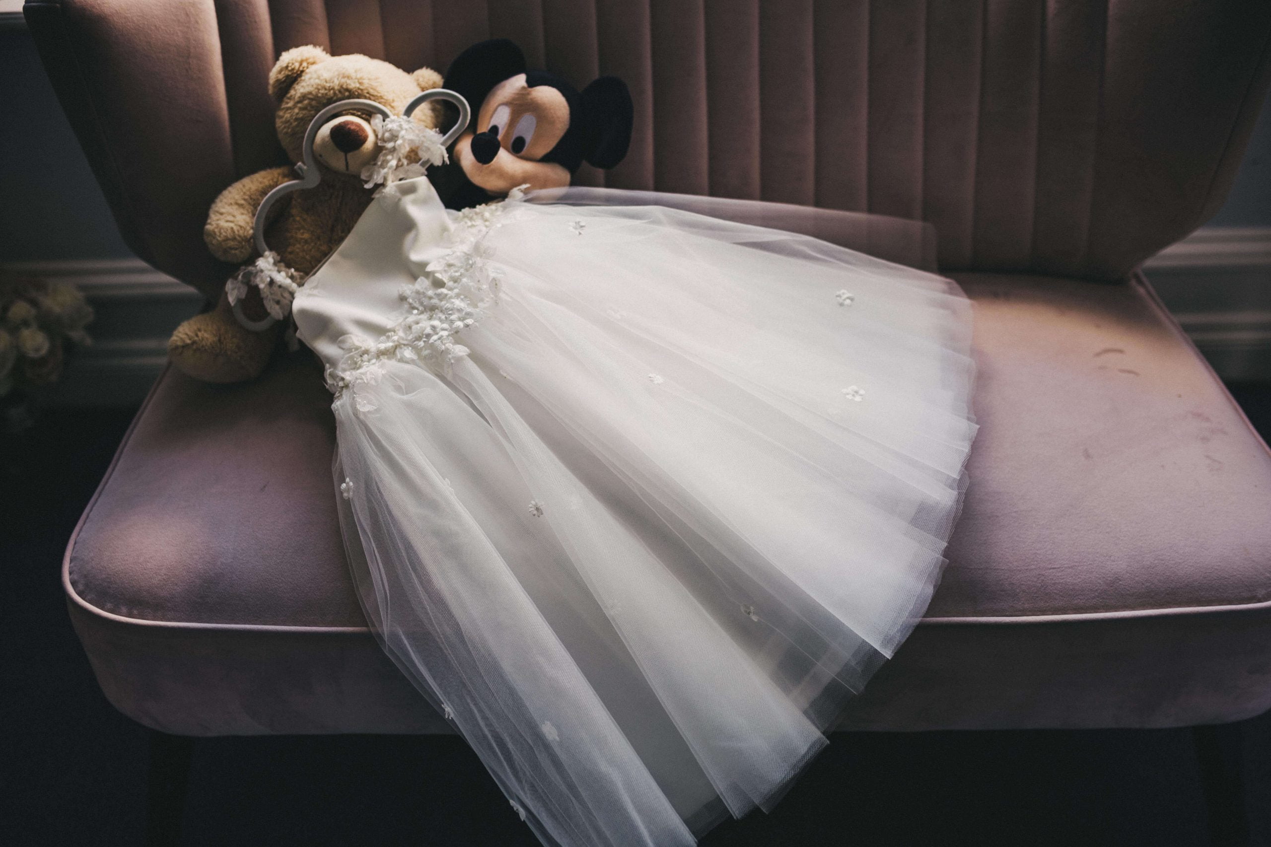Bridesmaids dress, teddy bear and mickey mouse soft toy on a pink velvet chair in the Bridal Lounge at Swynford Manor