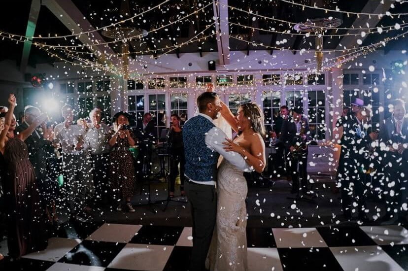 Bride and groom first dance on the chequerboard dance floor at Swynfor manor with coloured confetti falling