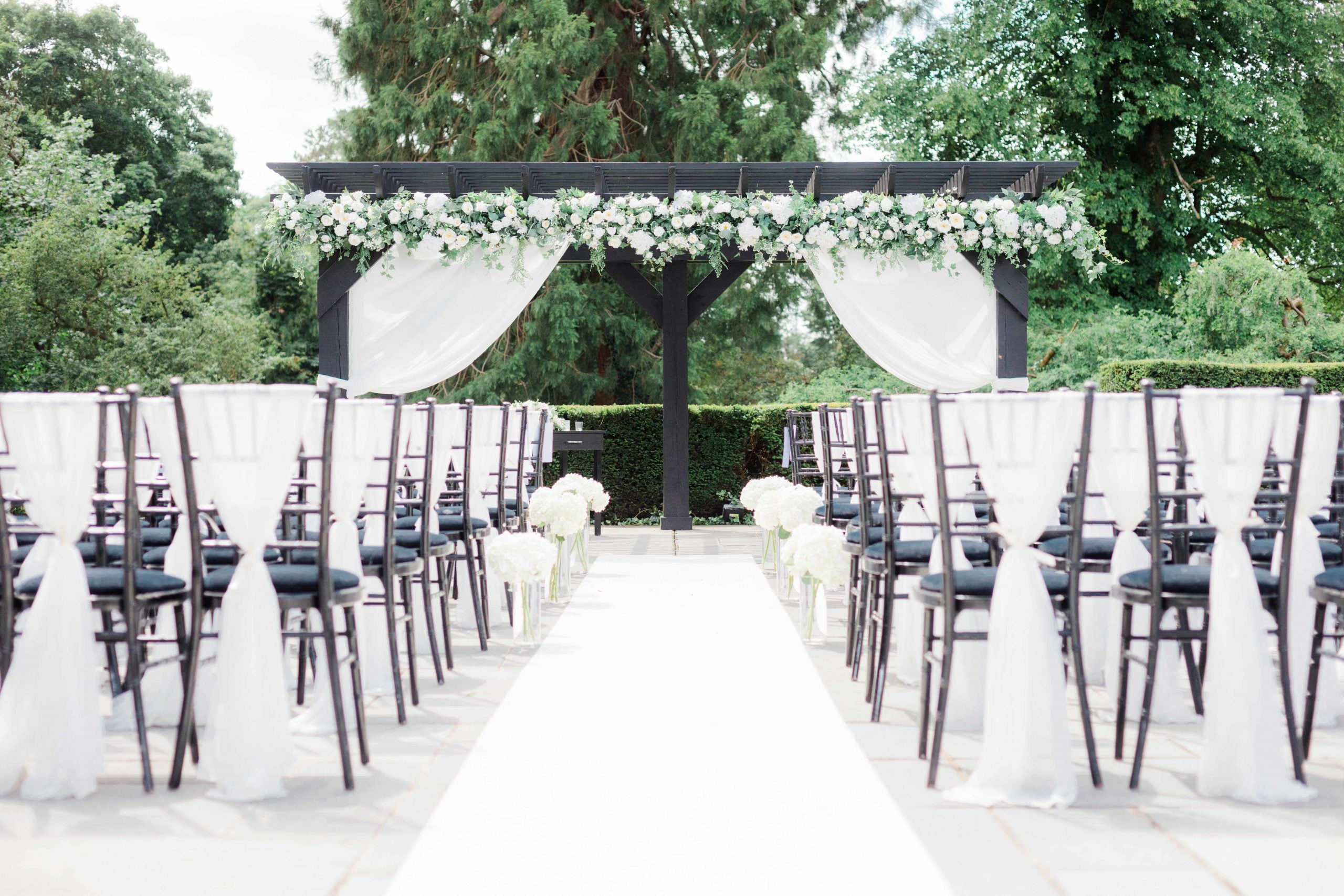 The pergola and ceremony chairs dressed in white voile for an outdoor wedding cerfemony at Swynford manor