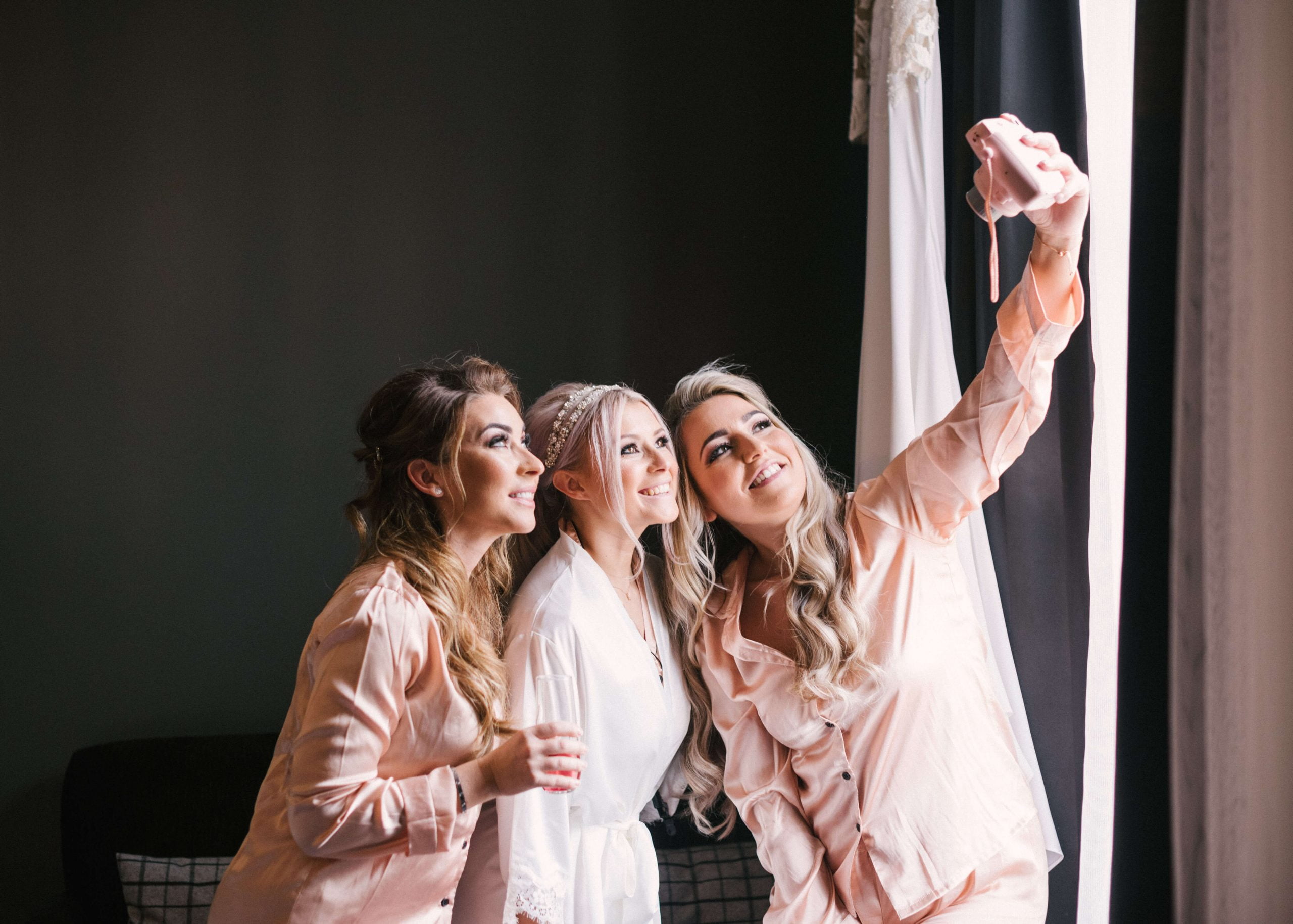 Bride and two bridesmaids in their blush pink pyjamas taking a selfie
